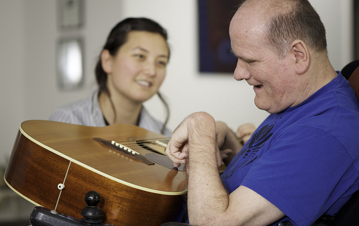 Man with disabiity, guitar, and a young woman